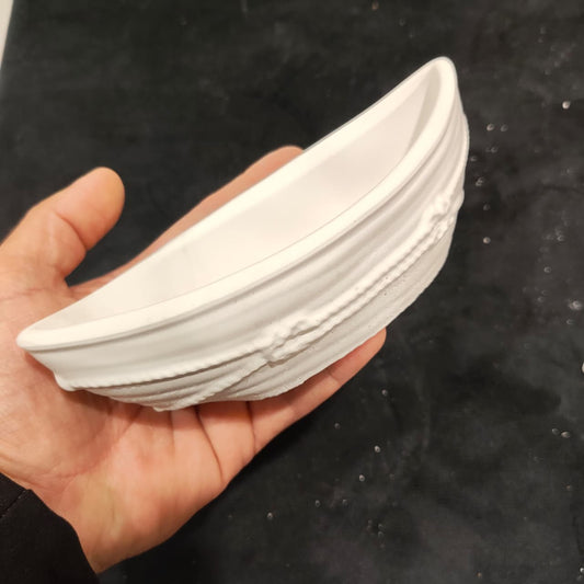 Hand holding a white ceramic bowl against a black background