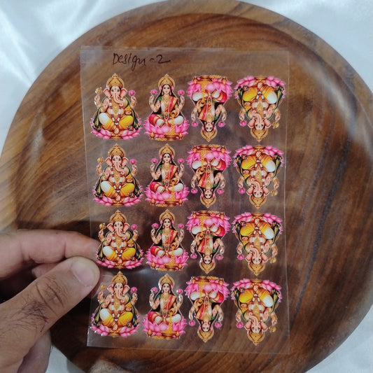 A sheet of 3D Lord Ganesha and Goddess Lakshmi UV DTF transfer stickers seated on lotus flowers held over a wooden plate for resin art and candle jar crafts
